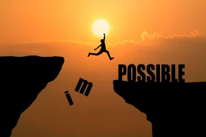 Poster inspirant montrant une silhouette de personne sautant d'une falaise à une autre, transformant 'IMPOSSIBLE' en 'POSSIBLE' sur un fond de coucher de soleil